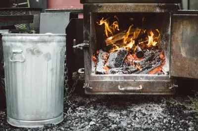 A wood burning oven next to an aluminum trash bin
