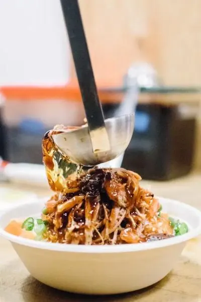 ladling sauce on a rice bowl