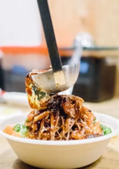 ladling sauce on a rice bowl